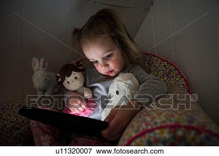 Female toddler sitting up in bed staring at digital tablet View Large Photo Image Stock Photo - Female toddler sitting up in bed staring at digital tablet. Fotosearch