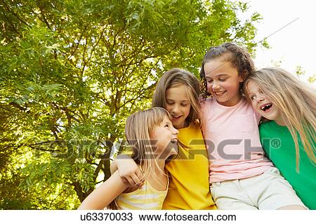 Four girls with arms around each other in park View Large Photo Image Stock Image - Four girls with arms around each other in park. Fotosearch