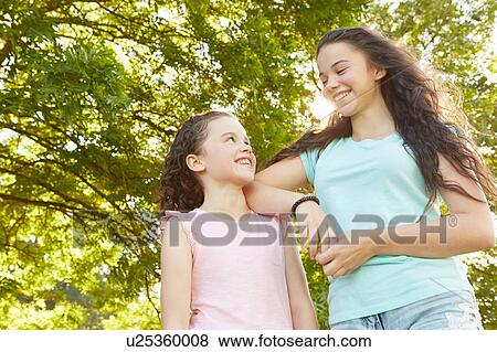 Girl and big sister looking at each other in park View Large Photo Image Stock Photo - Girl and big sister looking at each other in park. Fotosearch