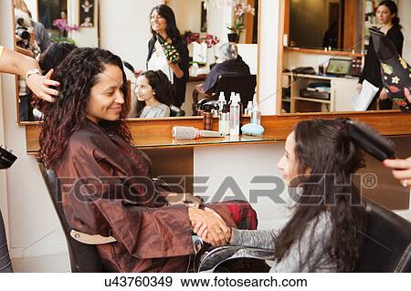 Girl and mother holding hands while having their hair styled in hair salon View Large Photo Image Stock Photo - Girl and mother holding hands while having their hair styled in hair salon. Fotosearch
