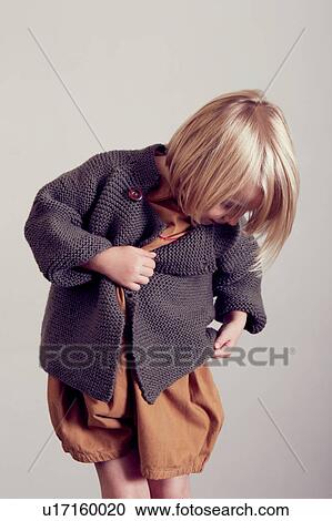 Stock Image - Girl examining hand knitted cardigan. Fotosearch