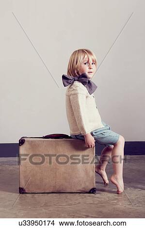 Girl in tied bow sitting on vintage suitcase View Large Photo Image Picture - Girl in tied bow sitting on vintage suitcase. Fotosearch