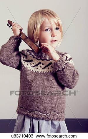Stock Image - Girl listening to old wooden toy guitar. Fotosearch