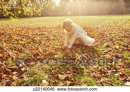 Stock Photograph - Girl picking up autumn leaves. Fotosearch