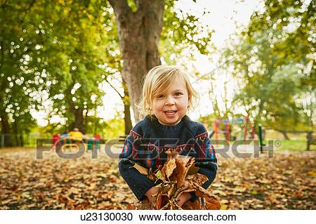 Stock Image - Girl playing in autumn leaves. Fotosearch