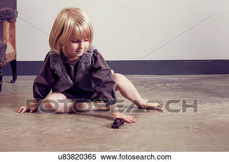 Stock Photography - Girl playing on floor with old wooden toy locomotive. Fotosearch