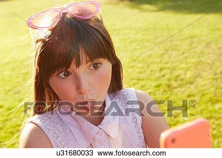 Girl pulling face for smartphone selfie on playing field View Large Photo Image Stock Image - Girl pulling face for smartphone selfie on playing field. Fotosearch