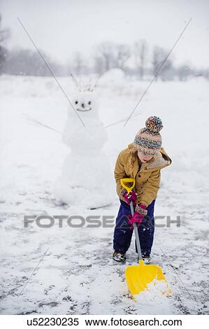 Girl shovelling snow in front of snowman, Lakefield, Ontario, Canada View Large Photo Image Stock Photography - Girl shovelling snow in front of snowman, Lakefield, Ontario, Canada. Fotosearch