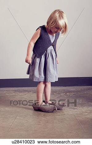 Stock Image - Girl standing in vintage wooden clogs looking down. Fotosearch