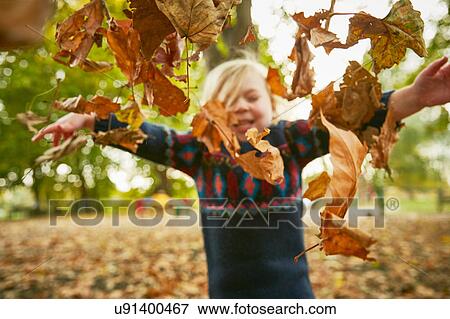 Stock Photo - Girl throwing in autumn leaves. Fotosearch