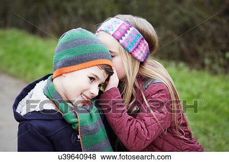 Girl whispering to boy on rural road View Large Photo Image Stock Photo - Girl whispering to boy on rural road. Fotosearch