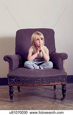 Girl with hands together sitting cross legged on vintage armchair View Large Photo Image Stock Image - Girl with hands together sitting cross legged on vintage armchair. Fotosearch