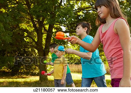 Girls and boys doing egg and spoon race in park View Large Photo Image Stock Photo - Girls and boys doing egg and spoon race in park. Fotosearch