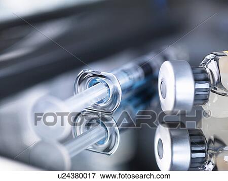 Stock Photo - Glass vial of medicine and syringe on surgical tray, close-up. Fotosearch