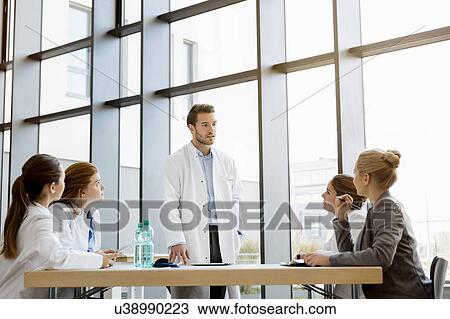 Stock Image - Group of doctors in meeting with consultant. Fotosearch