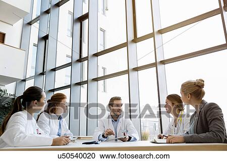 Stock Image - Group of doctors in meeting with consultant. Fotosearch