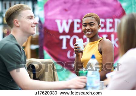 Stock Image - Group of friends, outdoors, drinking canned drinks. Fotosearch