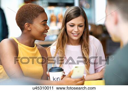 Group of friends, outdoors, looking at smartphone View Large Photo Image Stock Image - Group of friends, outdoors, looking at smartphone. Fotosearch