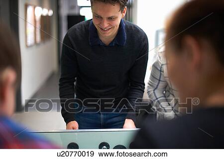 Stock Photo - Group of friends playing table football. Fotosearch