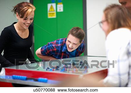 Stock Photo - Group of friends playing table football. Fotosearch