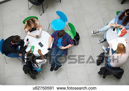Stock Image - Group of friends sitting in cafeteria, elevated view. Fotosearch