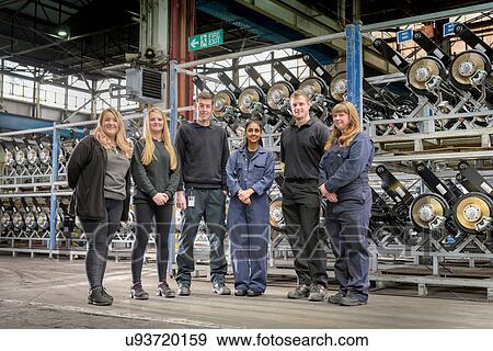 Stock Photo - Group portrait of male and female apprentices in car factory. Fotosearch