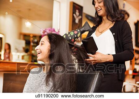 Hairdresser and girl laughing while having blow dry in hair salon View Large Photo Image Stock Image - Hairdresser and girl laughing while having blow dry in hair salon. Fotosearch