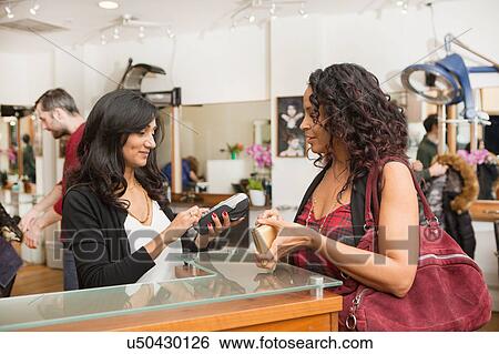Hairdresser getting receipt for female customer in hair salon View Large Photo Image Stock Photograph - Hairdresser getting receipt for female customer in hair salon. Fotosearch