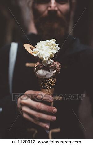 Stock Image - Hand of man holding gelato in dark alley, Venice, Italy. Fotosearch