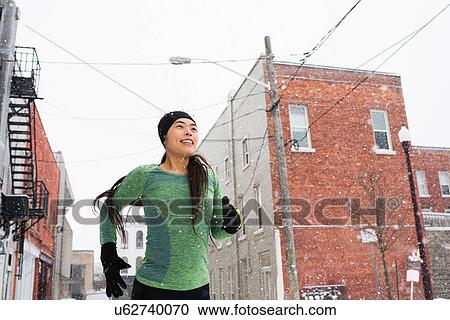 Happy young female runner in knit hat running in snowy street View Large Photo Image Stock Image - Happy young female runner in knit hat running in snowy street. Fotosearch
