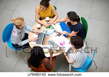 Stock Image - High angle view of business women sitting at table in meeting. Fotosearch