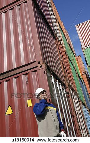 Picture - Industrial worker on cell phone with cargo containers. Fotosearch
