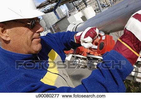 Stock Photo - Industrial worker turning wheel on pipeline. Fotosearch