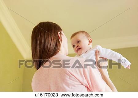 Low angle view of mid adult woman holding baby daughter in bedroom View Large Photo Image Stock Image - Low angle view of mid adult woman holding baby daughter in bedroom. Fotosearch