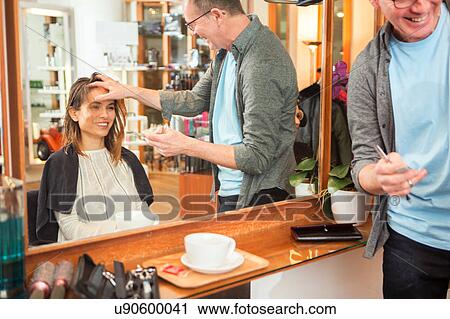 Stock Image - Male hairdresser advising female customer in hair salon. Fotosearch