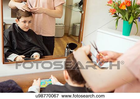 Stock Photo - Male hairdresser trimming boy's hair in hair salon. Fotosearch