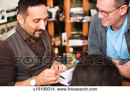 Picture - Male hairdressers advising customer on hairstyle in salon. Fotosearch