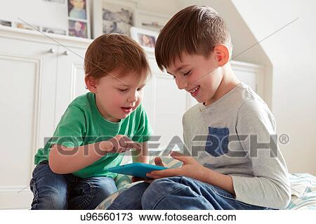 Male toddler and brother looking at digital tablet View Large Photo Image Stock Image - Male toddler and brother looking at digital tablet. Fotosearch
