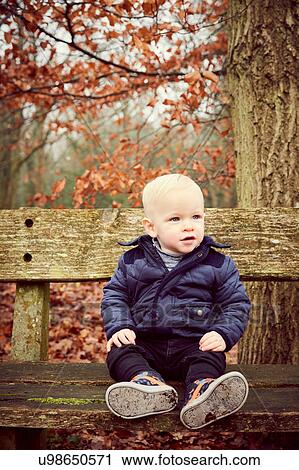 Male toddler sitting on park bench View Large Photo Image Stock Image - Male toddler sitting on park bench. Fotosearch
