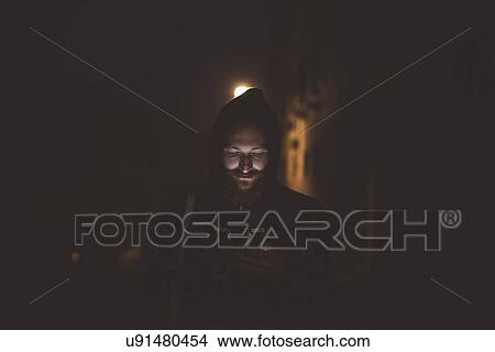 Man looking down at smartphone at night, Venice, Italy View Large Photo Image Picture - Man looking down at smartphone at night, Venice, Italy. Fotosearch