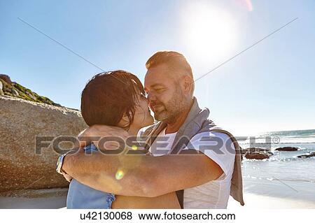 Stock Photo - Mature couple hugging on beach, Cape Town, South Africa. Fotosearch