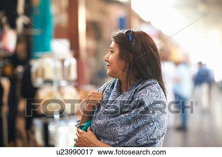 Stock Photo - Mature female tourist looking at market stall, Sharjah, United Arab Emirates. Fotosearch