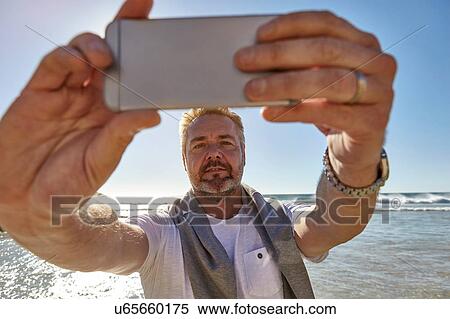 Mature man on beach, taking selfie with smartphone, Cape Town, South Africa View Large Photo Image Stock Photography - Mature man on beach, taking selfie with smartphone, Cape Town, South Africa. Fotosearch
