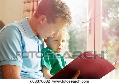 Mature man reading book to son on his lap View Large Photo Image Stock Image - Mature man reading book to son on his lap. Fotosearch
