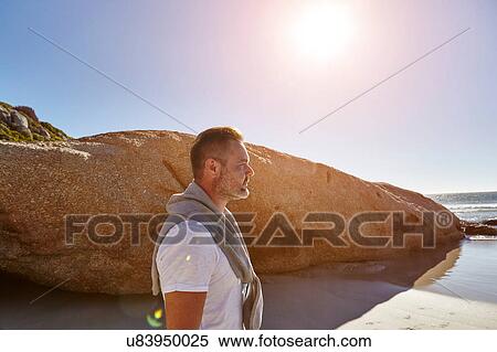 Stock Photography - Mature man standing on beach, looking at view, Cape Town, South Africa. Fotosearch