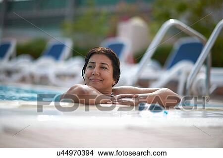 Mature woman leaning on swimming pool side, Dubai, United Arab Emirates View Large Photo Image Picture - Mature woman leaning on swimming pool side, Dubai, United Arab Emirates. Fotosearch
