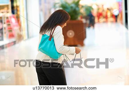 Mature woman looking at her shopping bag in shopping mall, Dubai, United Arab Emirates View Large Photo Image Stock Image - Mature woman looking at her shopping bag in shopping mall, Dubai, United Arab Emirates. Fotosearch