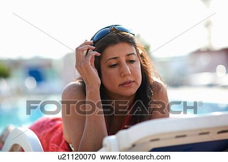 Mature woman lying on pool side lounger reading, Dubai, United Arab Emirates View Large Photo Image Stock Image - Mature woman lying on pool side lounger reading, Dubai, United Arab Emirates. Fotosearch