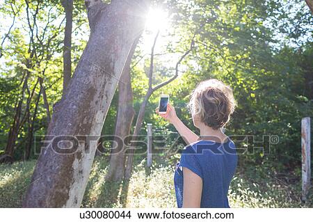 Picture - Mature woman photographing rainforest with smartphone, Nosara, Guanacaste Province, Costa Rica. Fotosearch