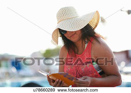Mature woman sitting at pool side reading guidebook, Dubai, United Arab Emirates View Large Photo Image Stock Photo - Mature woman sitting at pool side reading guidebook, Dubai, United Arab Emirates. Fotosearch